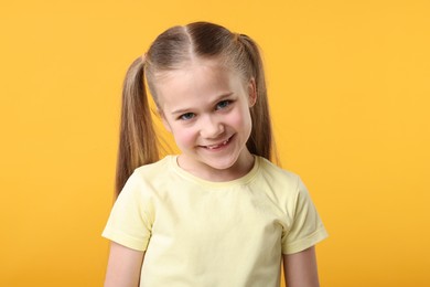 Photo of Portrait of cute little girl on orange background