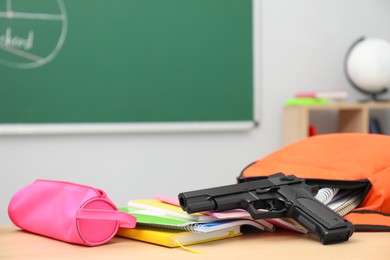 School stationery, gun and backpack on desk in classroom