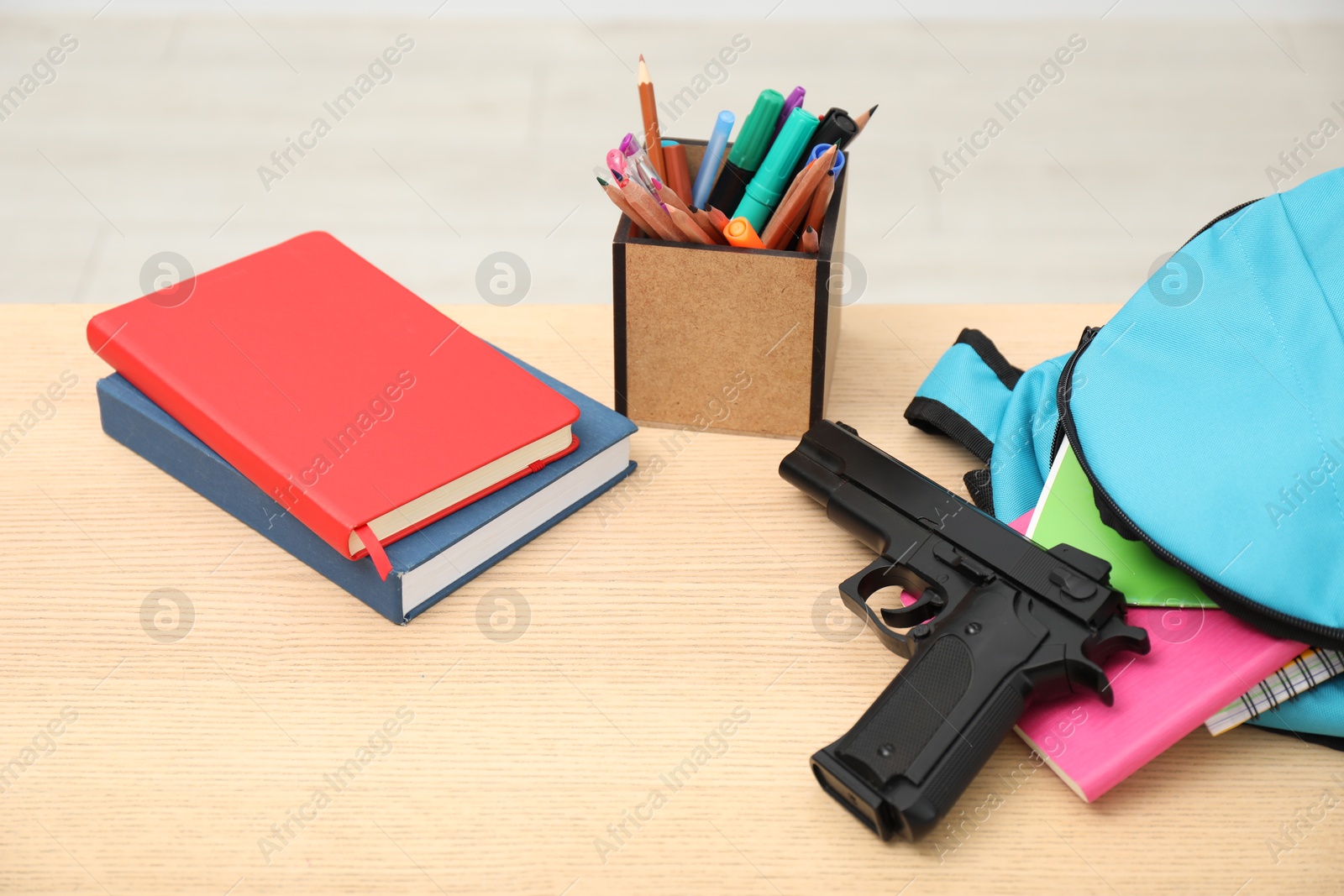 Photo of School stationery and gun on wooden desk, closeup