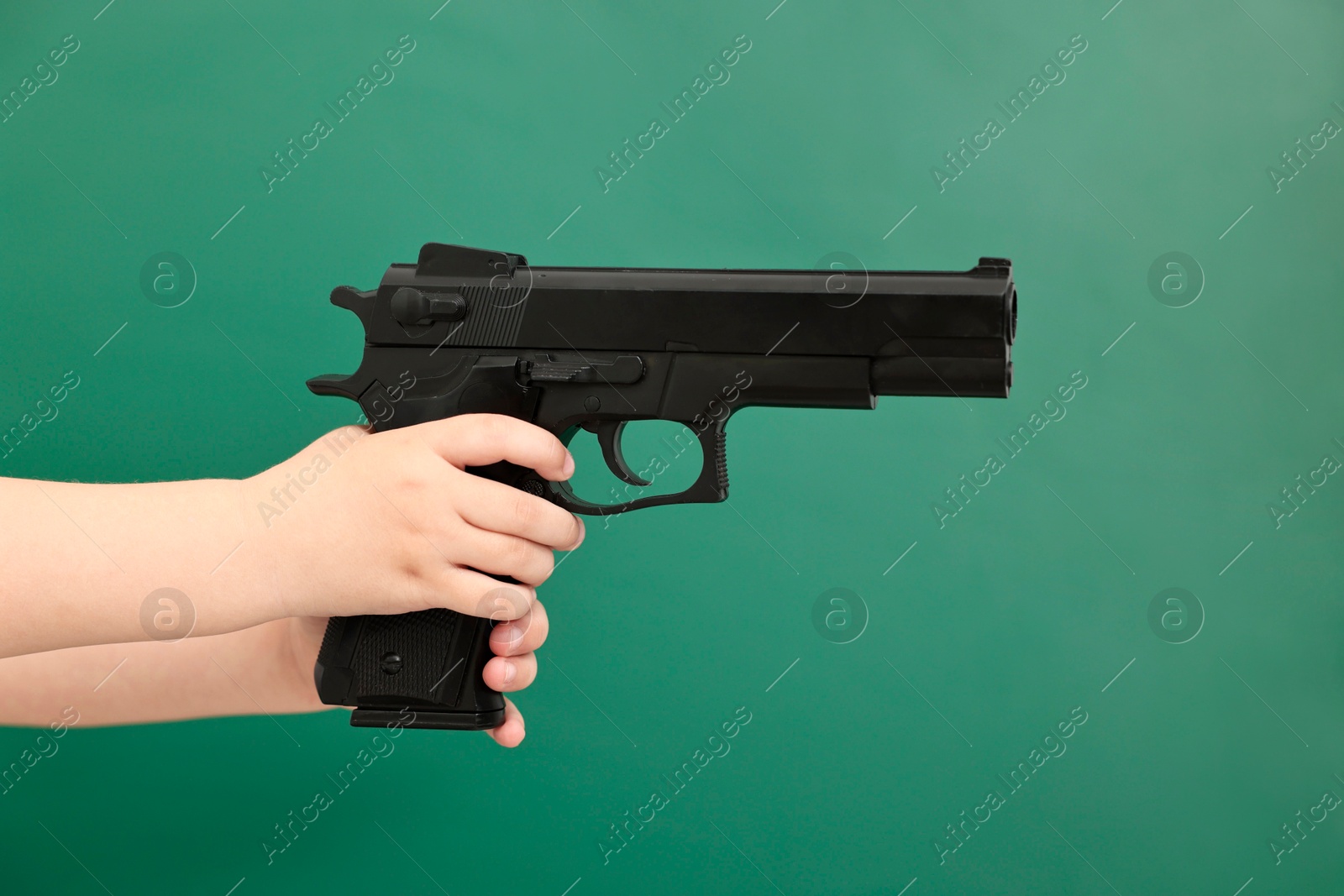 Photo of Child with gun against chalkboard, closeup. School shooting