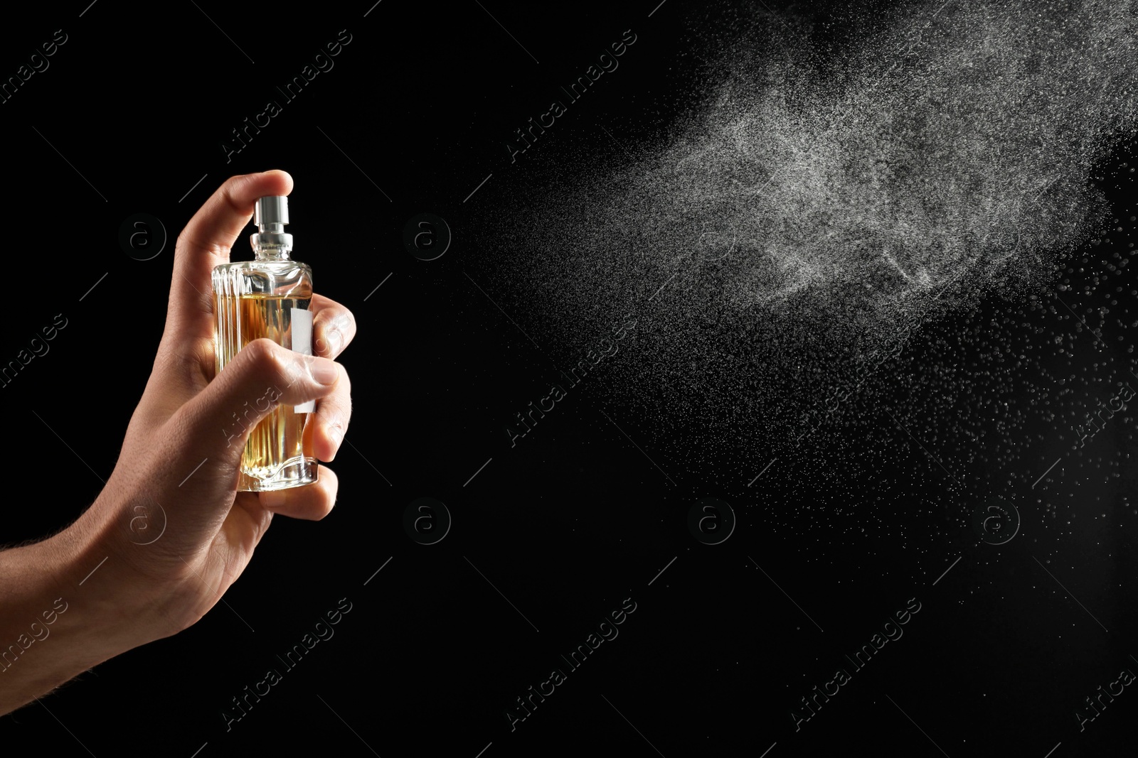 Photo of Man spraying luxury perfume on dark background, closeup. Space for text
