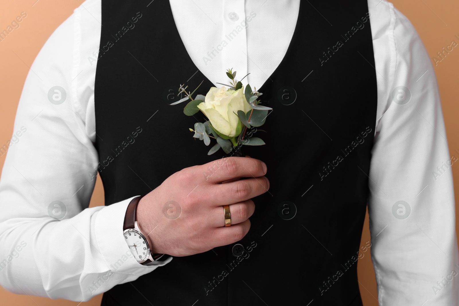 Photo of Groom with boutonniere on beige background, closeup. Wedding accessory