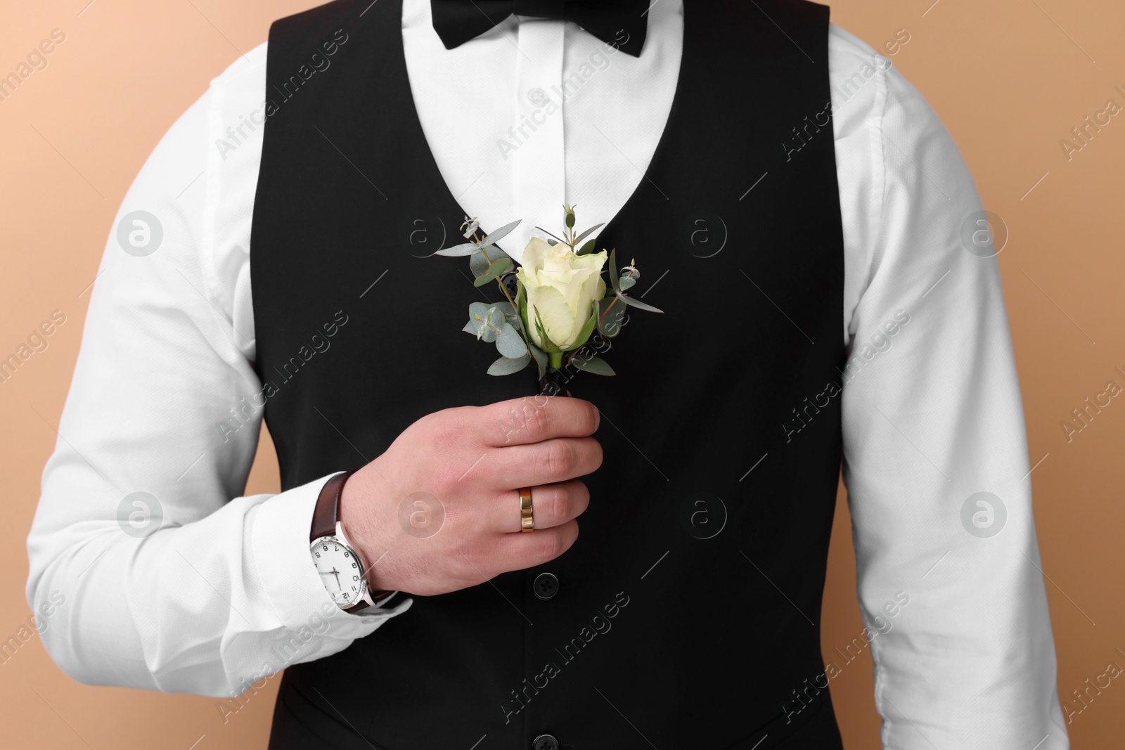 Photo of Groom with boutonniere on beige background, closeup. Wedding accessory