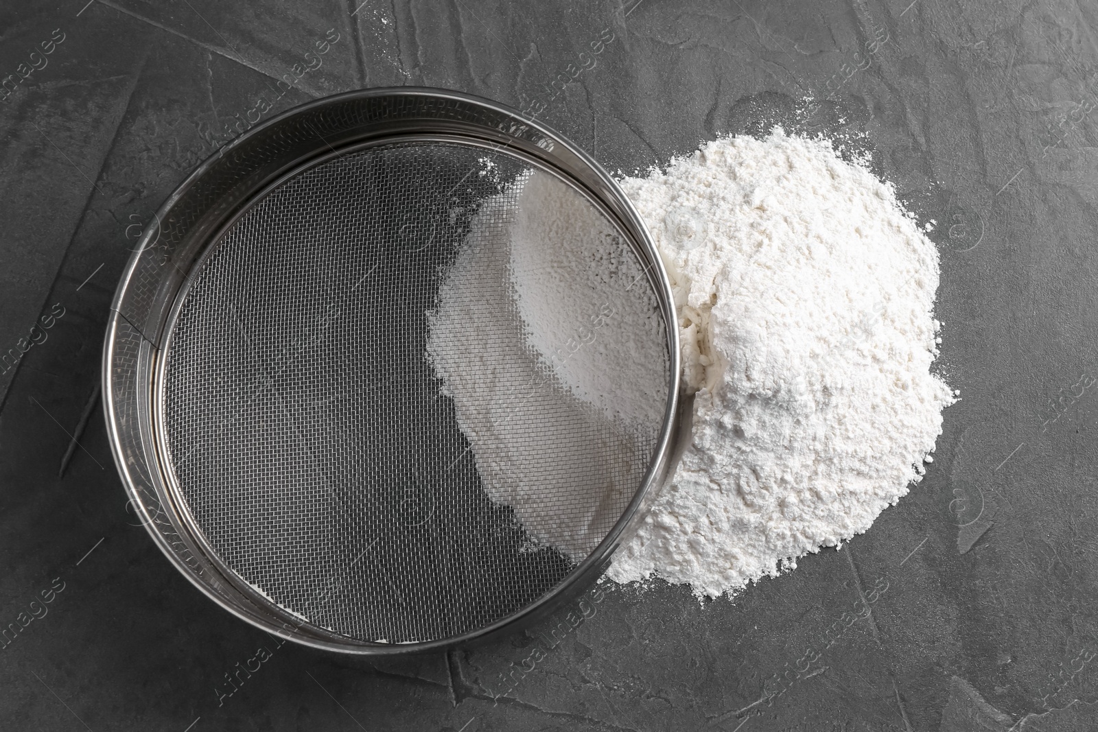 Photo of Metal sieve and flour on grey table, top view