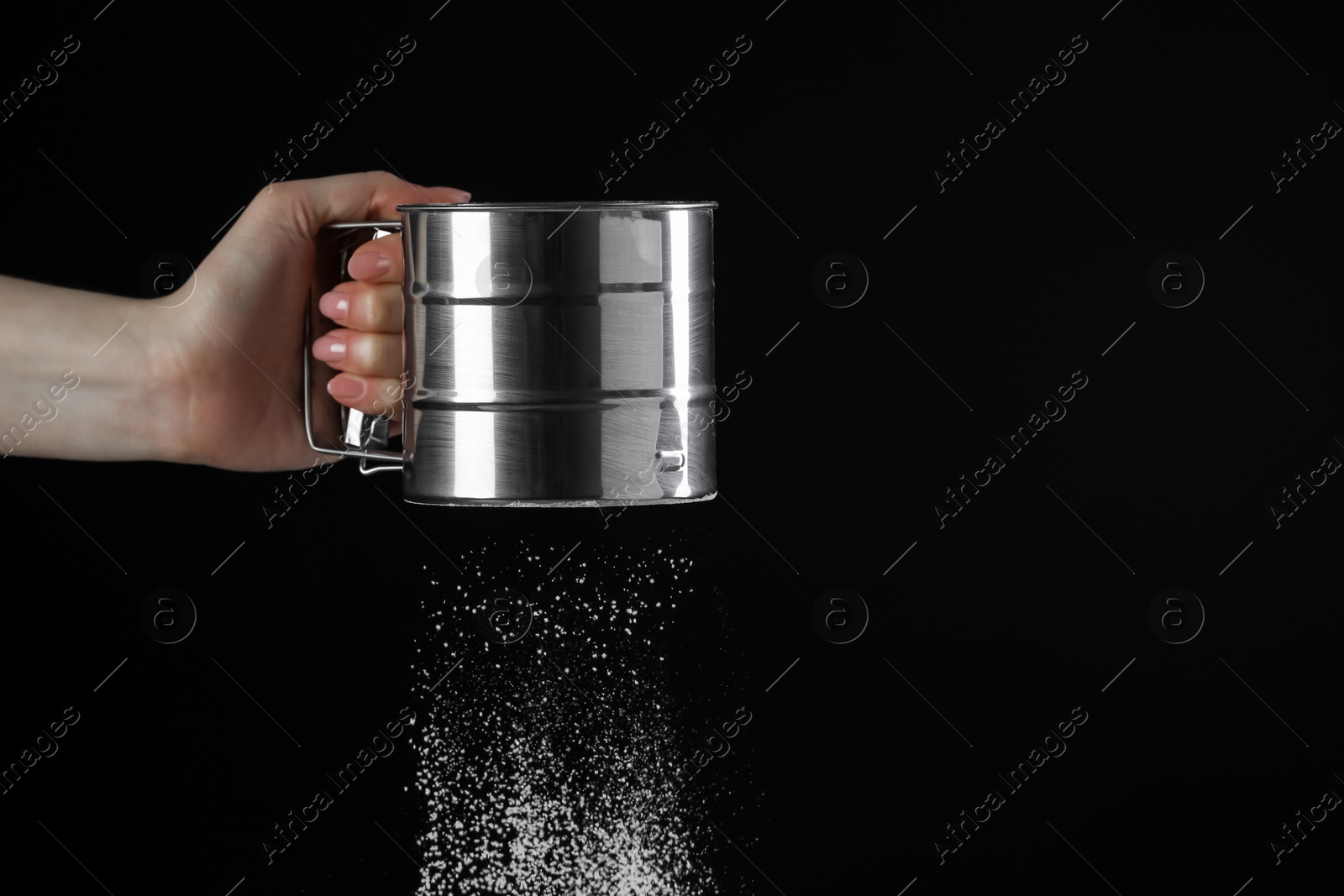 Photo of Woman sieving flour against black background, closeup. Space for text