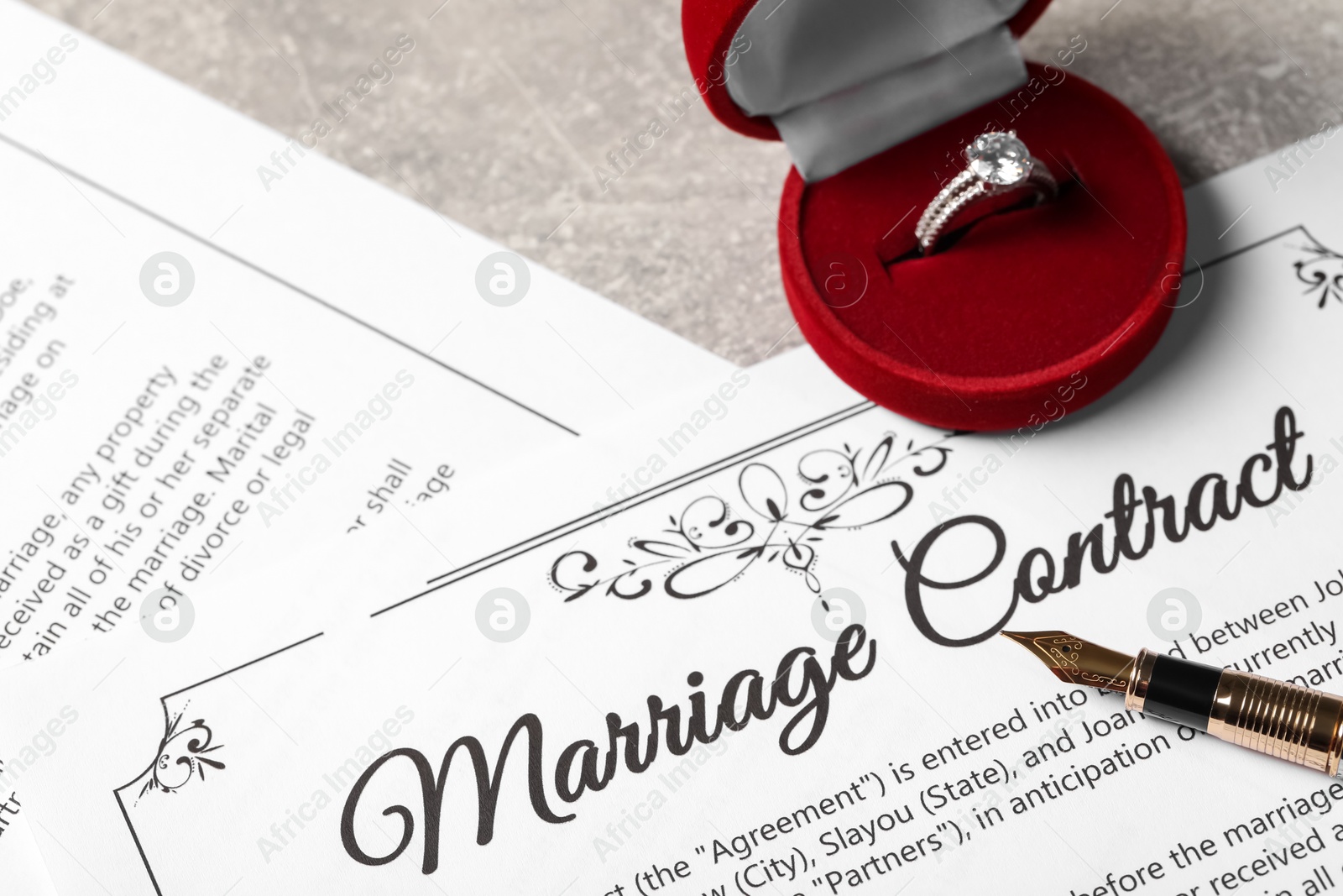 Photo of Marriage contract, fountain pen and ring with gemstone on grey table