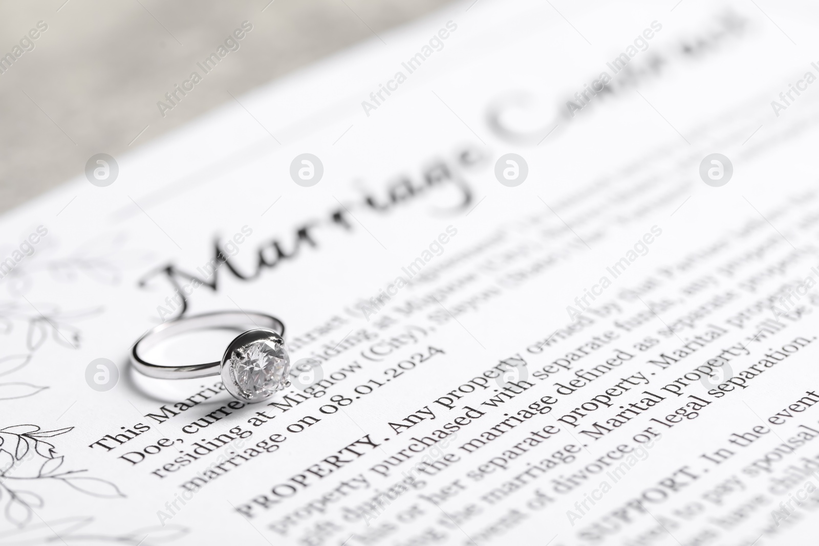 Photo of Marriage contract and ring with gemstone on grey table, closeup