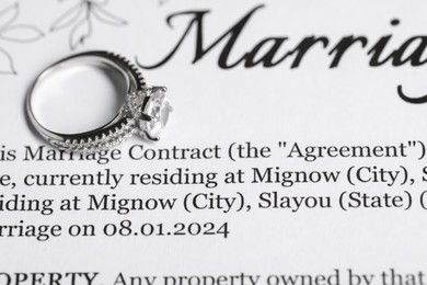 Photo of Marriage contract and ring with gemstone, closeup