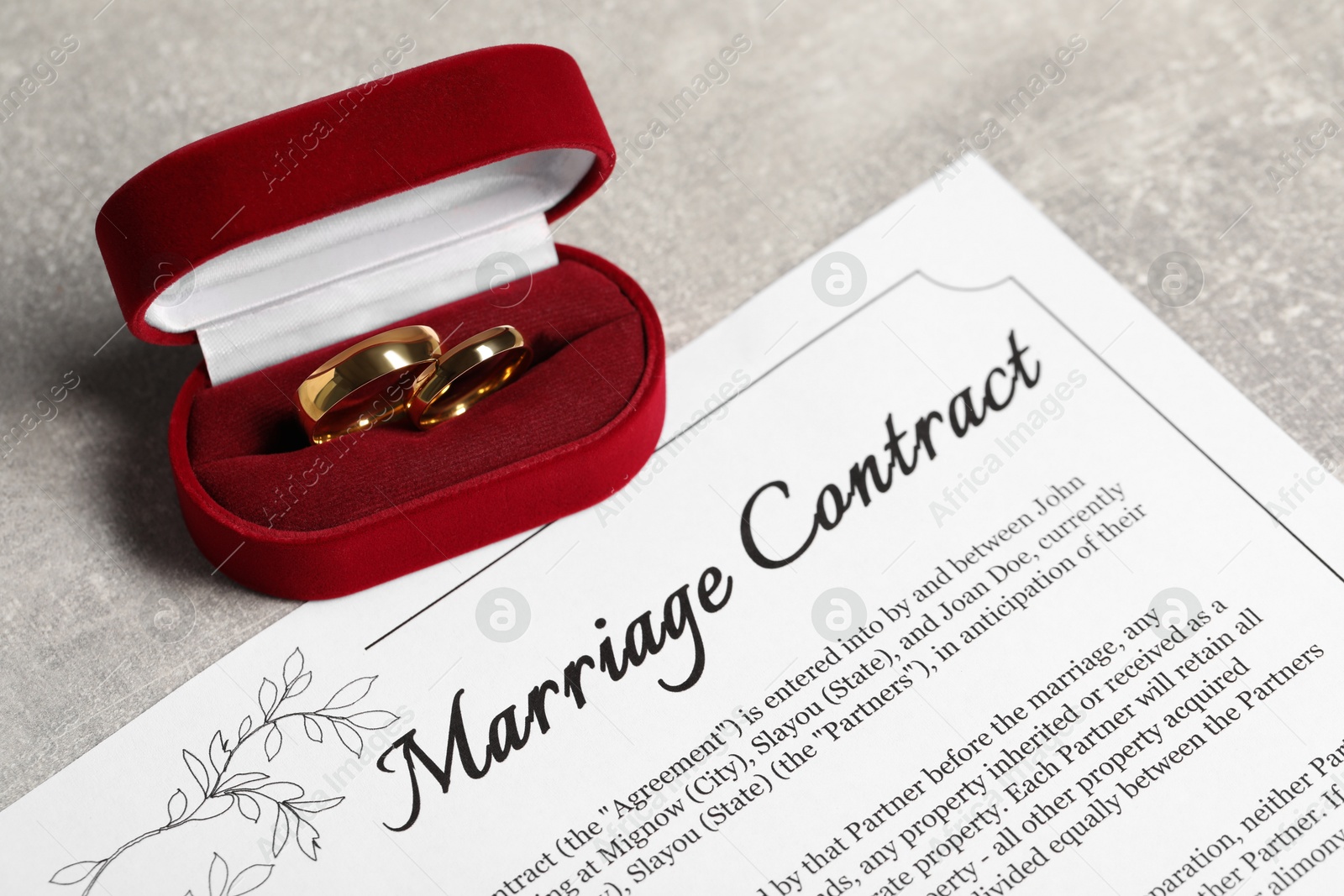 Photo of Marriage contract and golden wedding rings on grey table