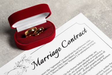 Photo of Marriage contract and golden wedding rings on grey table