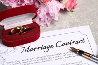 Photo of Marriage contract, fountain pen and wedding rings on table, closeup