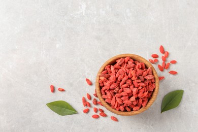 Photo of Dried goji berries in bowl on light grey table, top view. Space for text