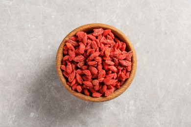 Photo of Dried goji berries in bowl on light grey table, top view