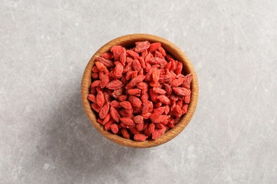 Dried goji berries in bowl on light grey table, top view