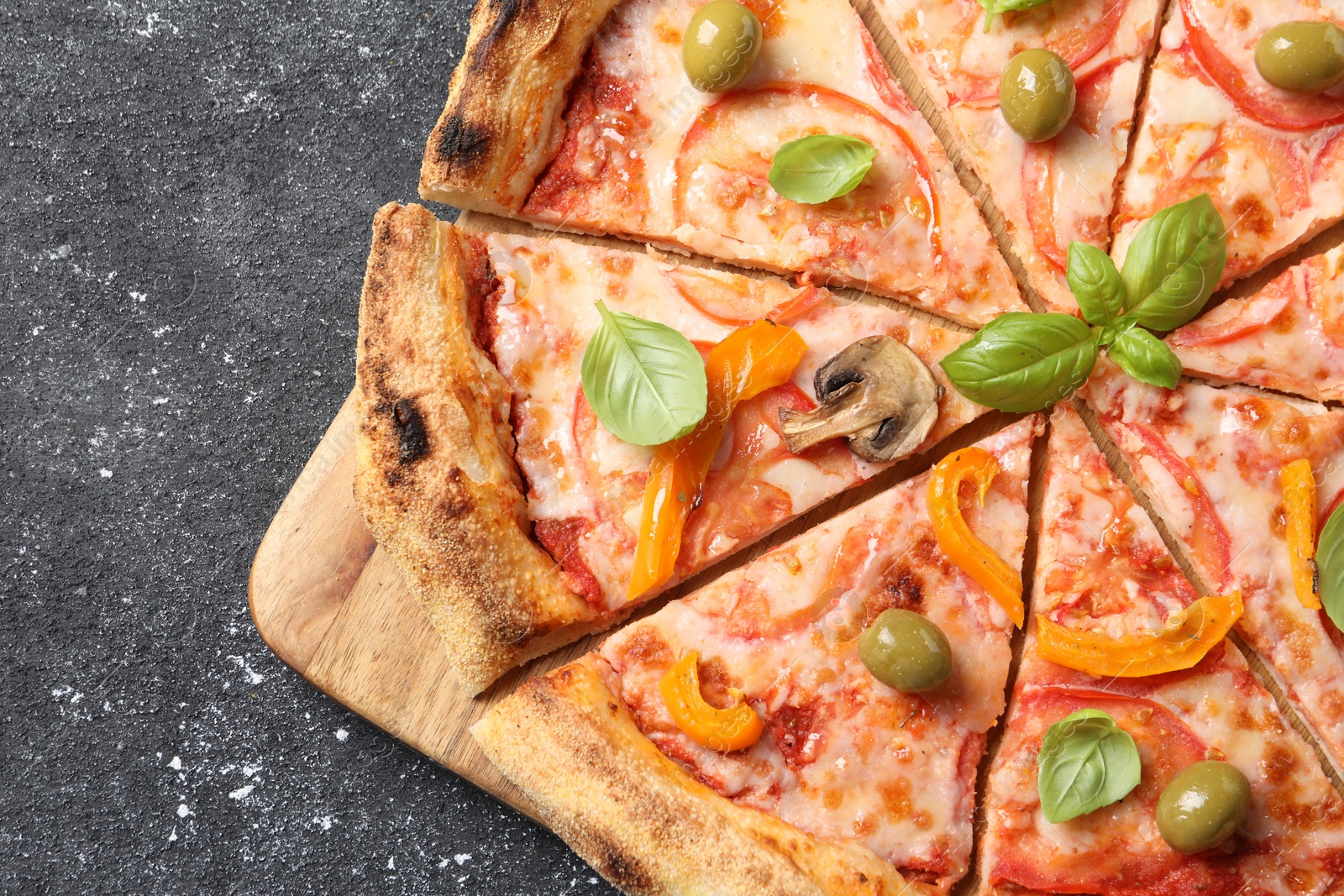 Photo of Cut delicious vegetarian pizza on grey table, top view