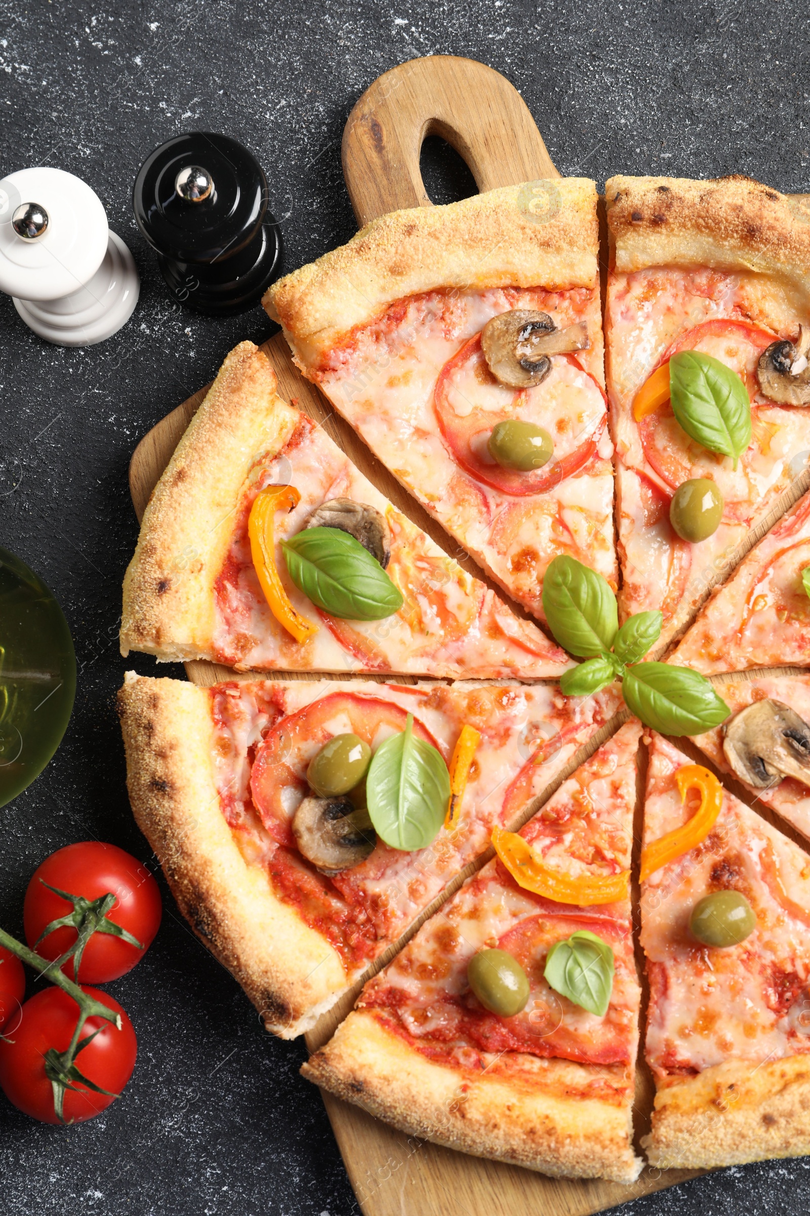 Photo of Cut delicious vegetarian pizza, tomatoes and spices on grey table, top view