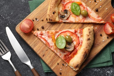 Photo of Cut delicious vegetarian pizza, spices, tomato and cutlery on grey table, top view