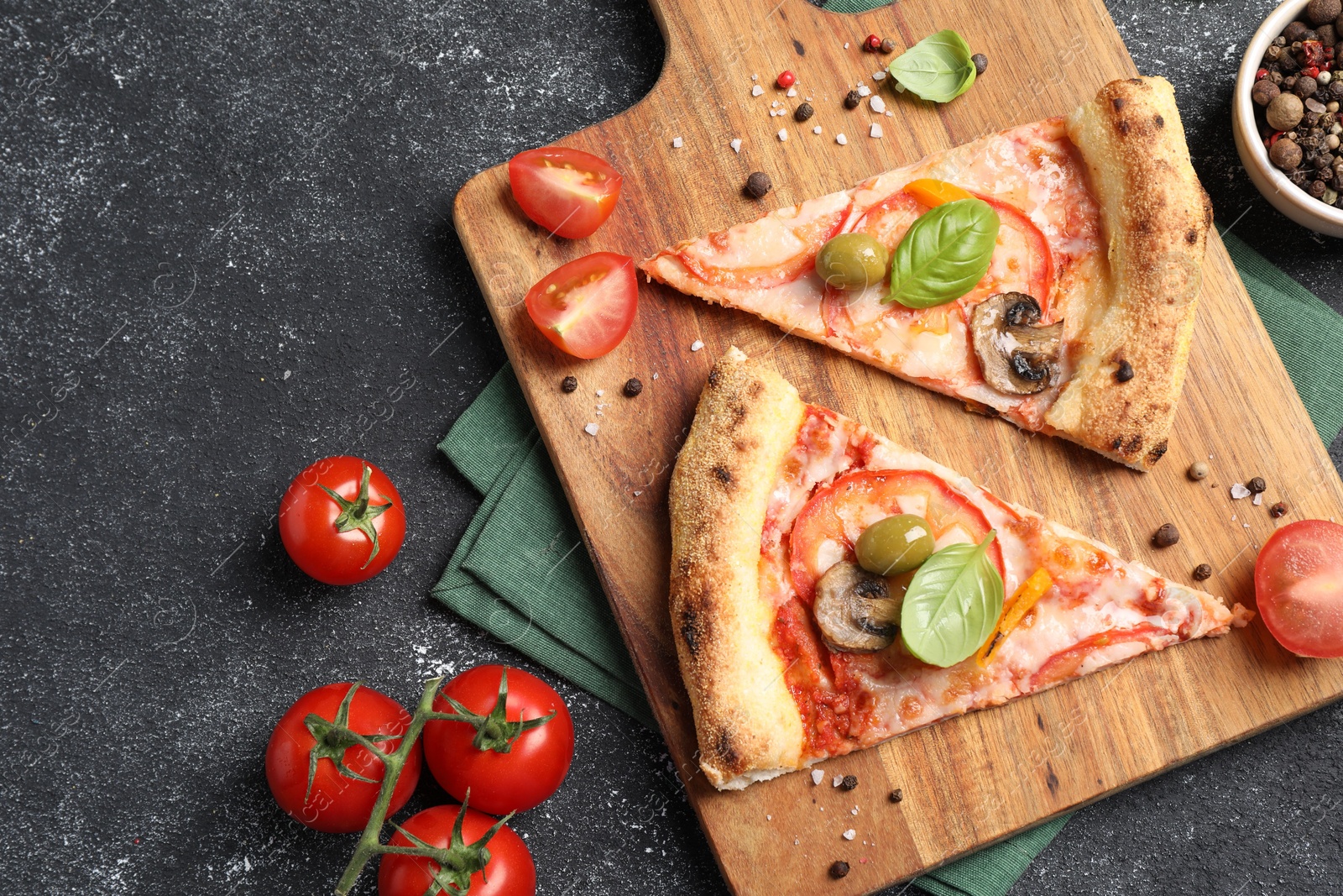 Photo of Cut delicious vegetarian pizza, spices and tomatoes on grey table, top view