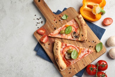 Photo of Cut delicious vegetarian pizza and ingredients on light grey table, top view. Space for text