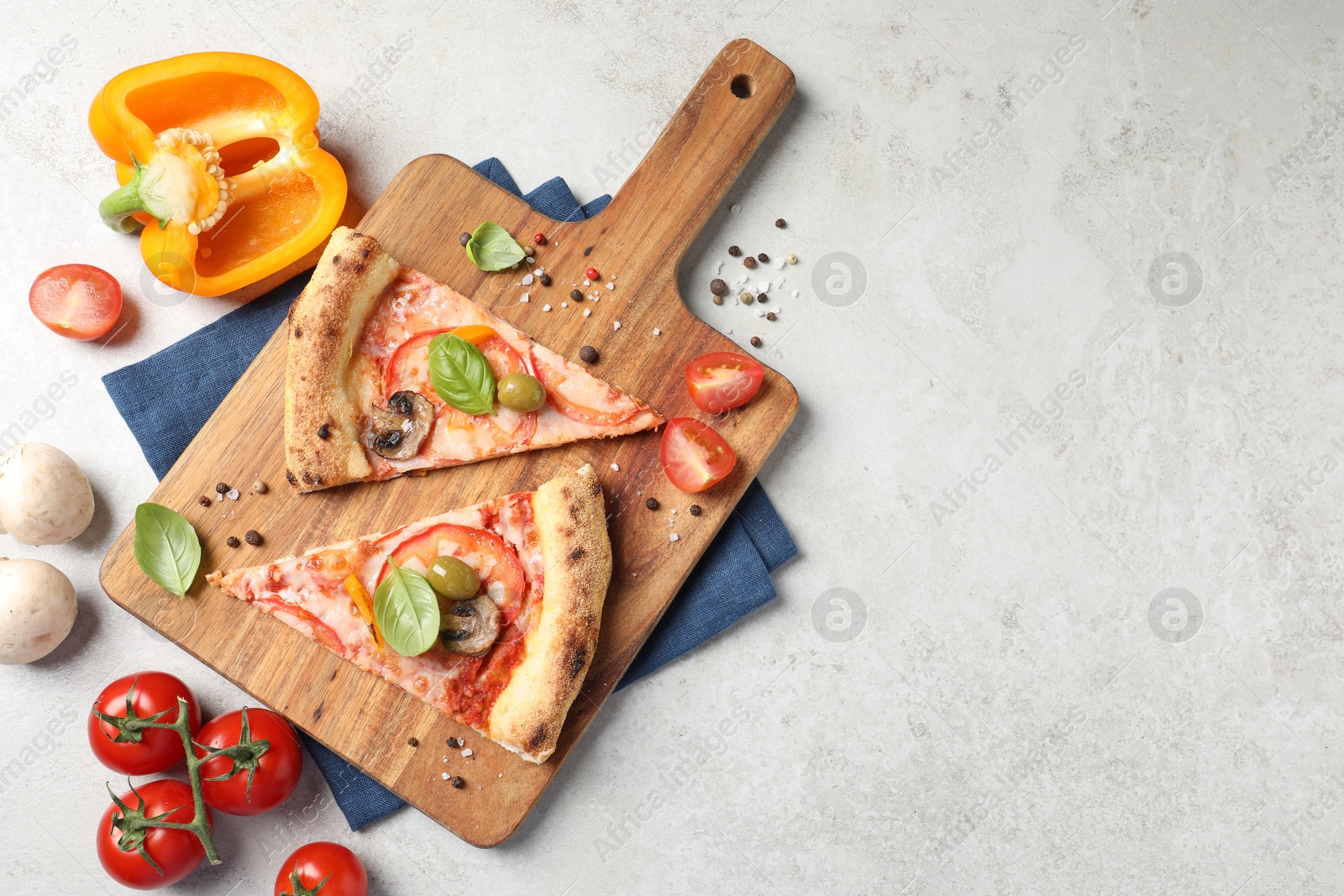 Photo of Cut delicious vegetarian pizza and ingredients on light grey table, top view. Space for text