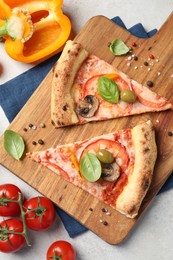 Photo of Cut delicious vegetarian pizza and ingredients on light grey table, top view