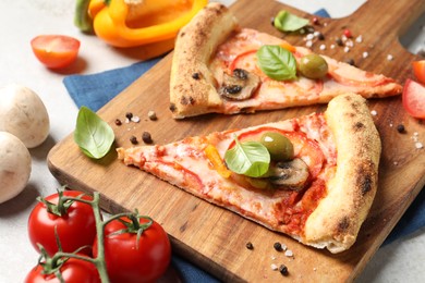 Photo of Cut delicious vegetarian pizza and ingredients on light grey table