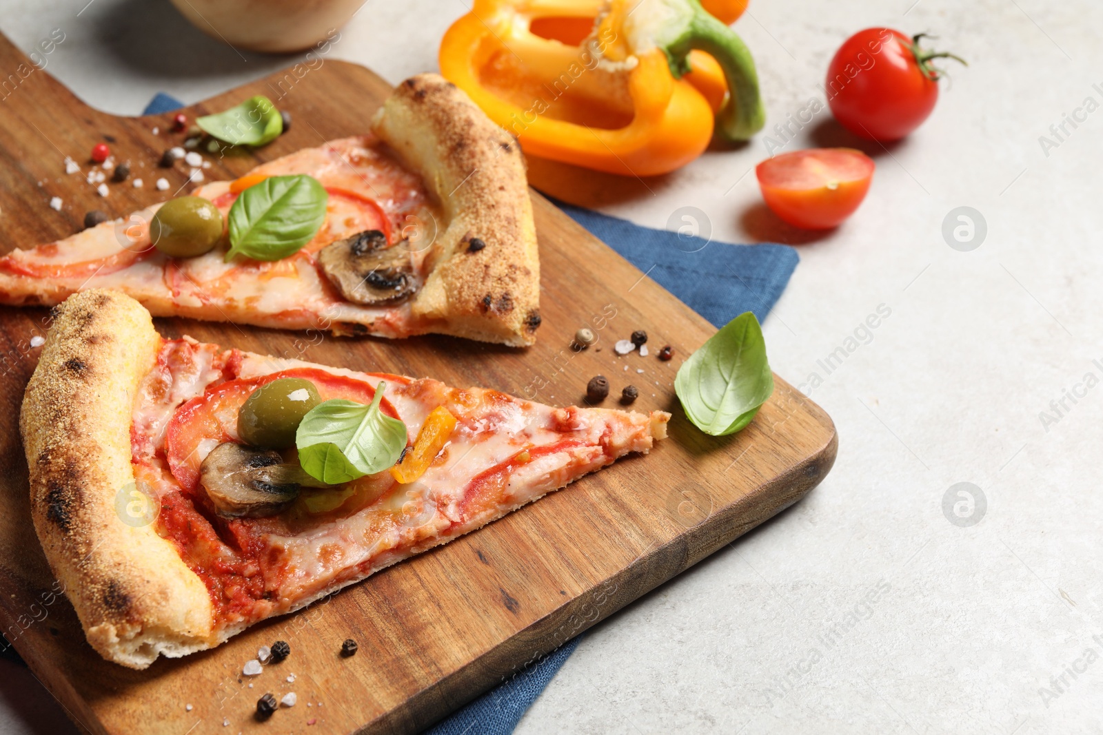 Photo of Cut delicious vegetarian pizza and ingredients on light grey table