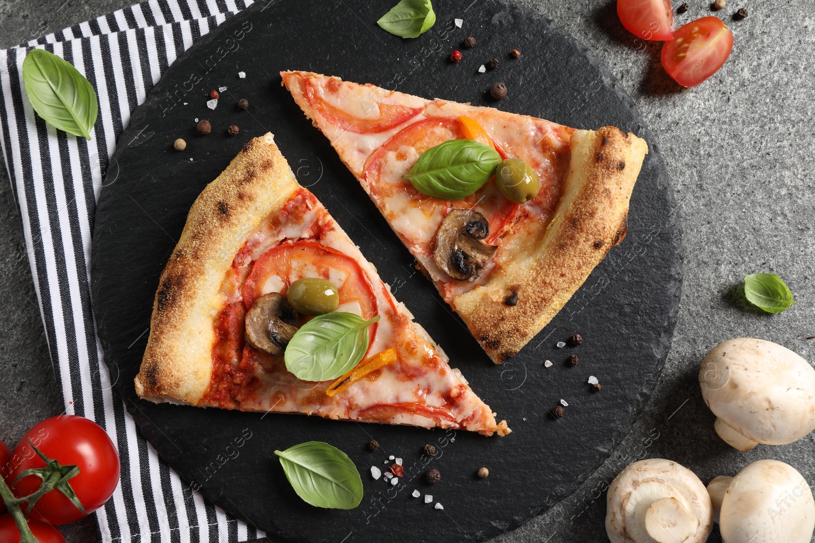 Photo of Cut delicious vegetarian pizza, spices, tomatoes and mushrooms on grey table, top view