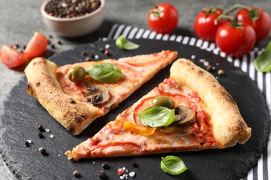 Photo of Cut delicious vegetarian pizza, spices and tomatoes on table