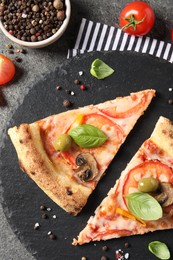 Photo of Cut delicious vegetarian pizza, spices and tomatoes on grey table, top view