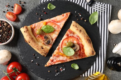 Photo of Cut delicious vegetarian pizza and ingredients on grey table, top view