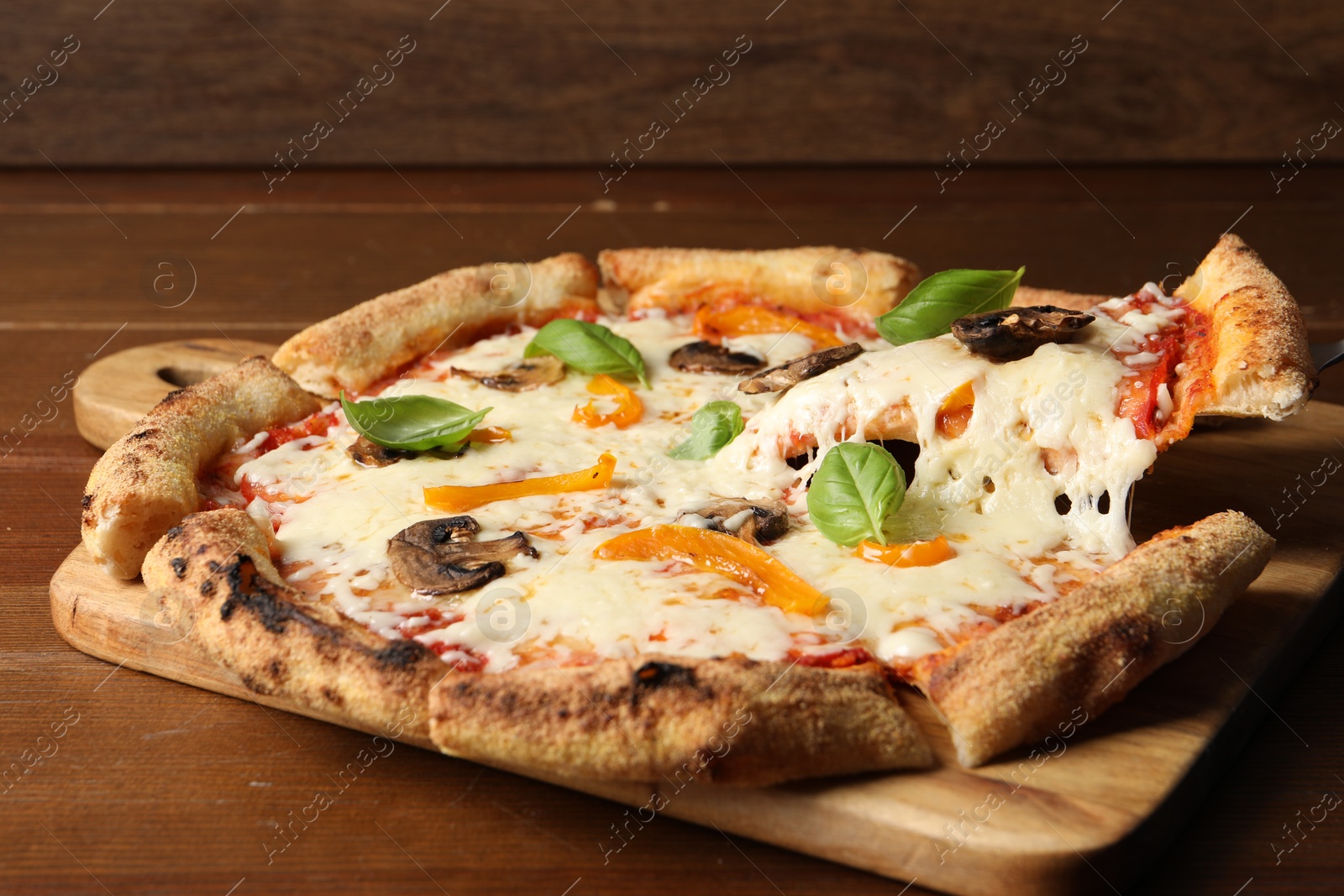 Photo of Taking piece of delicious vegetarian pizza at wooden table, closeup