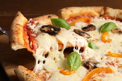 Photo of Taking piece of delicious vegetarian pizza at table, closeup