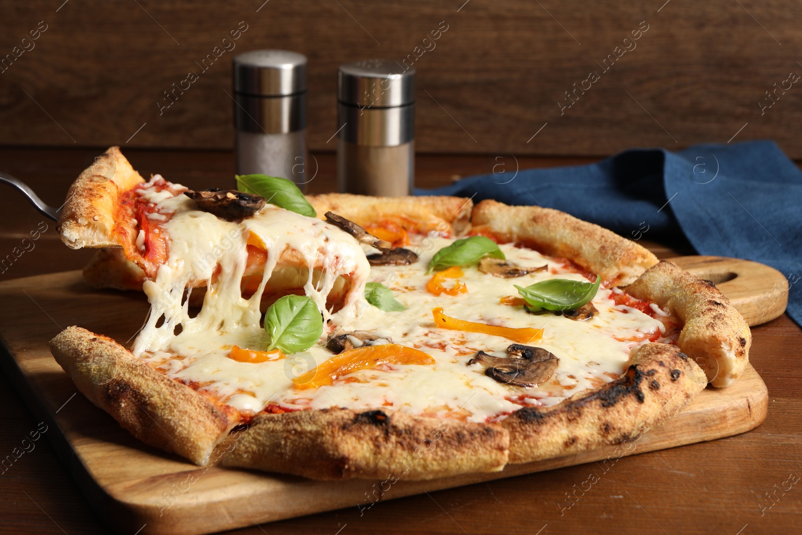 Photo of Taking piece of delicious vegetarian pizza at wooden table, closeup