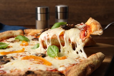 Photo of Taking piece of delicious vegetarian pizza at table, closeup