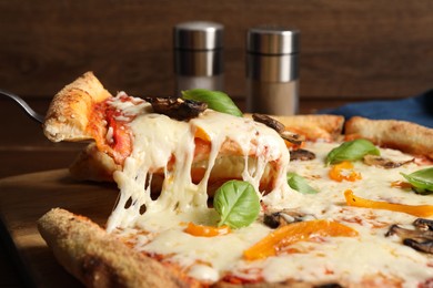 Photo of Taking piece of delicious vegetarian pizza at table, closeup