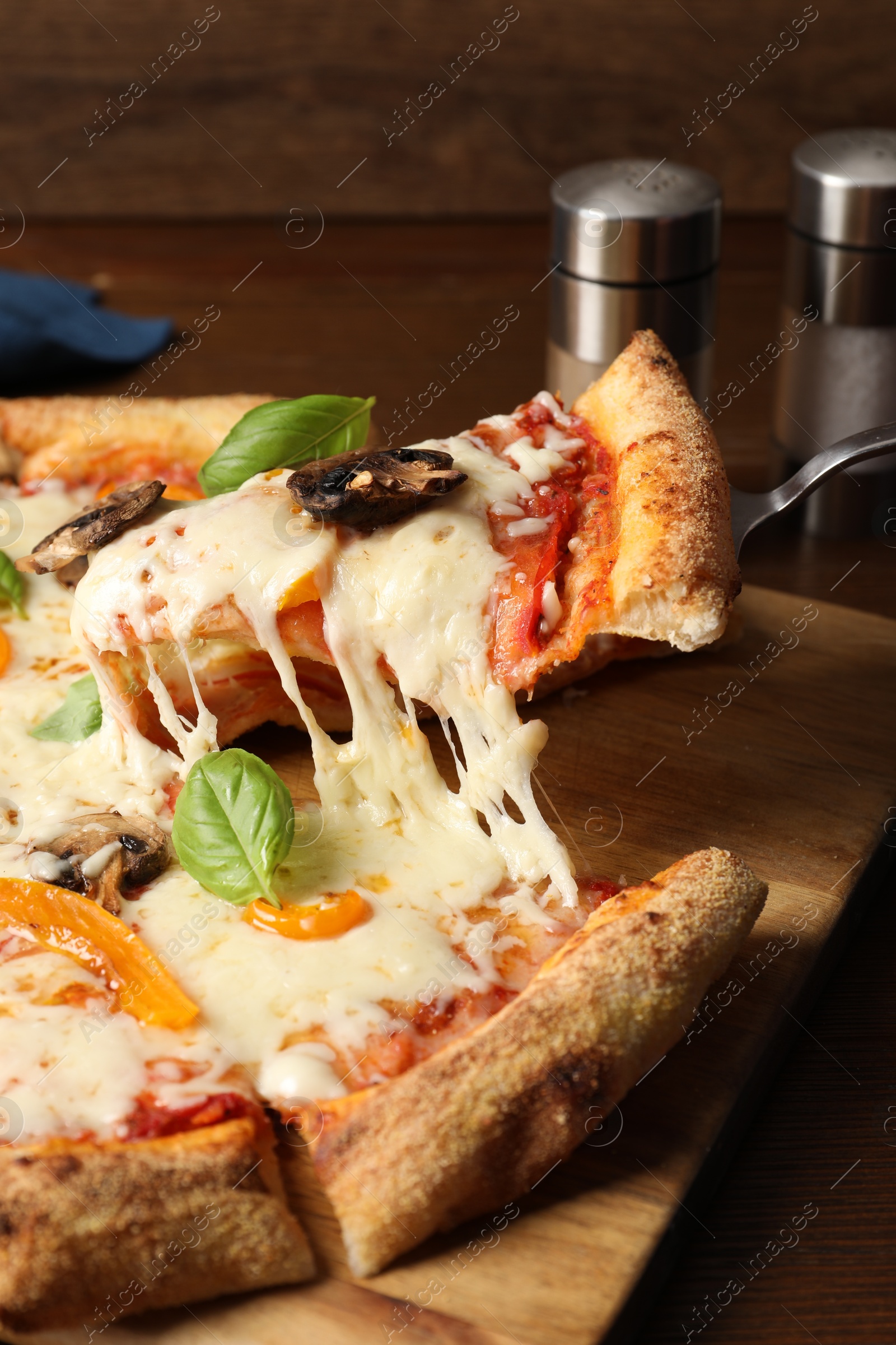 Photo of Taking piece of delicious vegetarian pizza at table, closeup