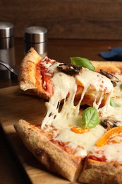 Photo of Taking piece of delicious vegetarian pizza at table, closeup