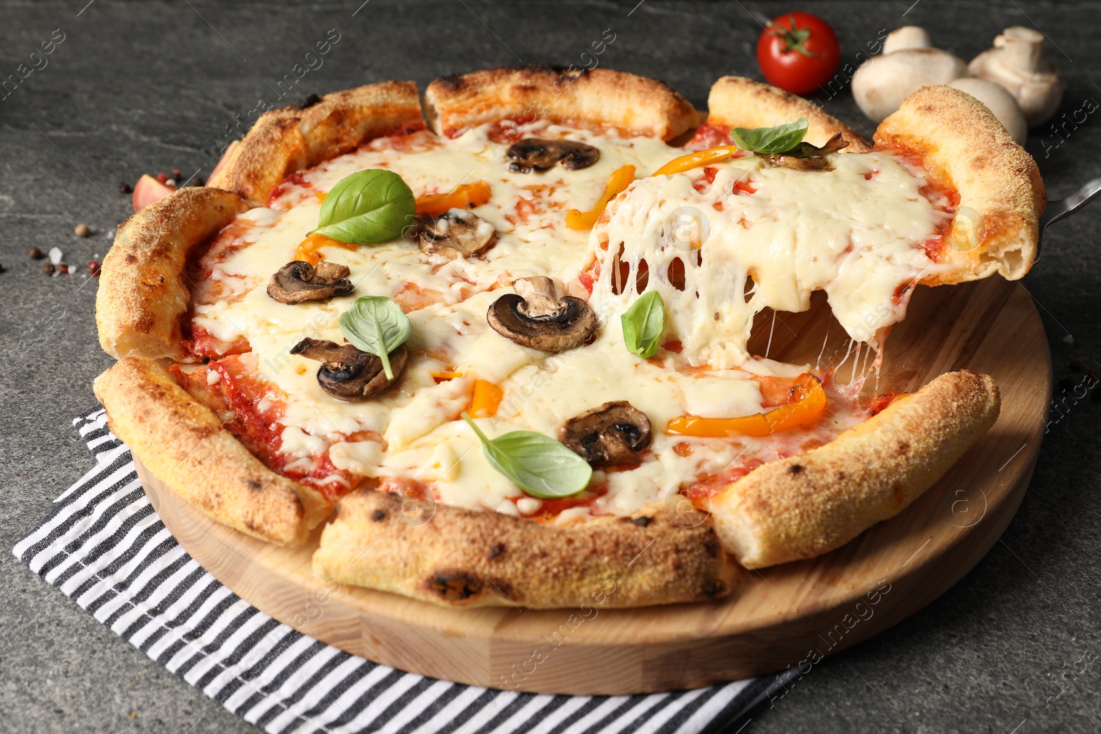 Photo of Taking piece of delicious vegetarian pizza at grey table, closeup