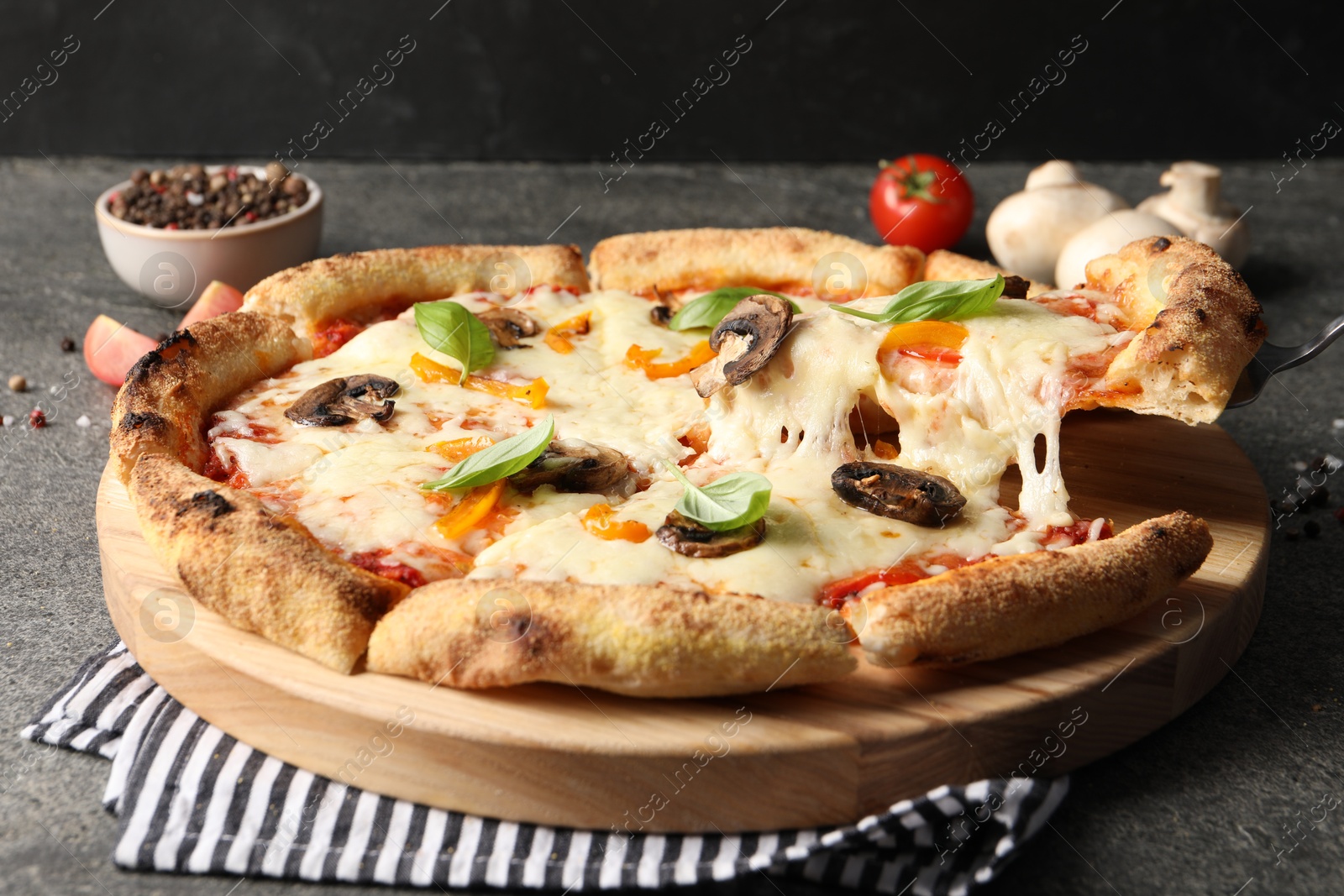 Photo of Taking piece of delicious vegetarian pizza at grey table, closeup