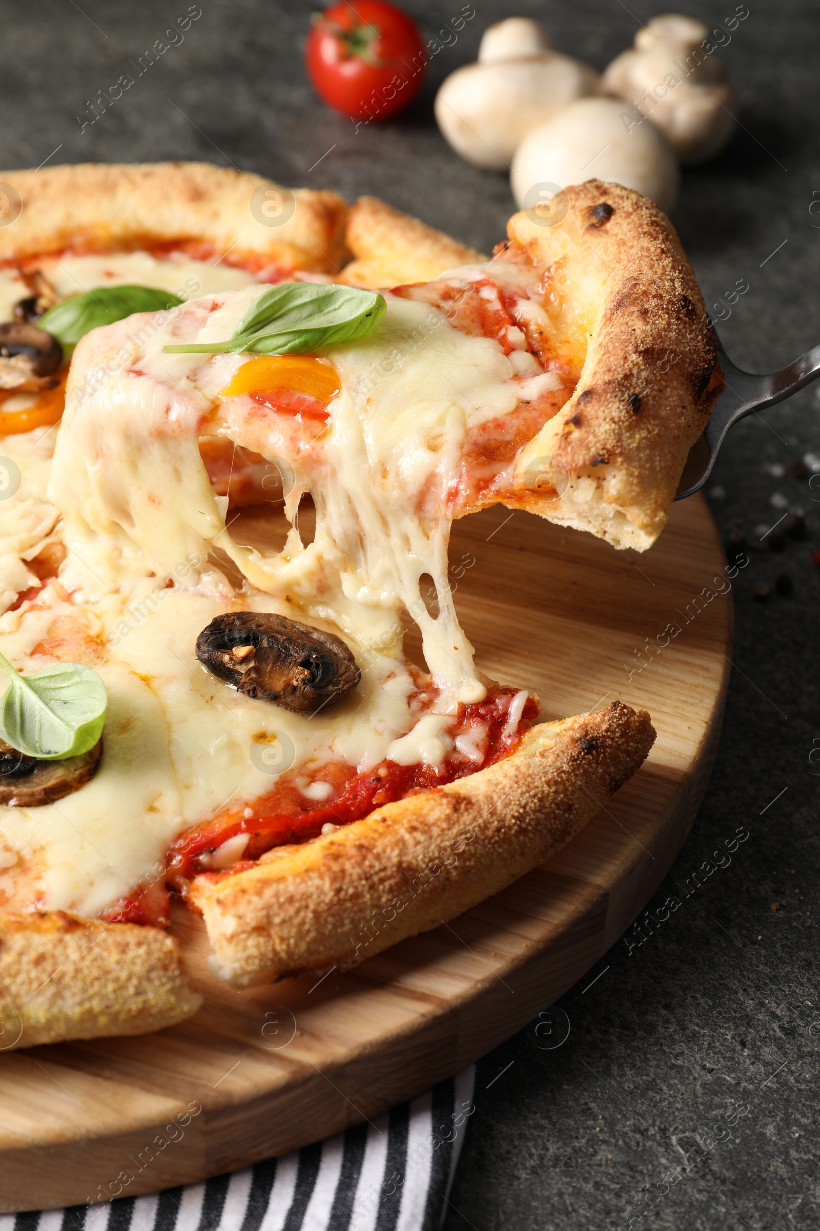 Photo of Taking piece of delicious vegetarian pizza at grey table, closeup