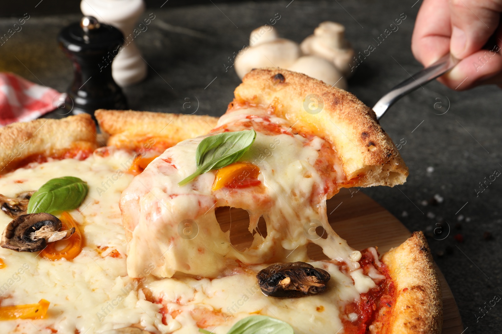 Photo of Man taking piece of delicious vegetarian pizza at grey table, closeup