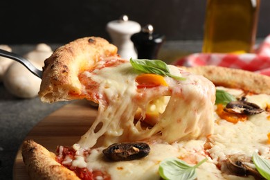 Photo of Taking piece of delicious vegetarian pizza at table, closeup