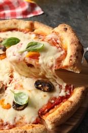 Photo of Taking piece of delicious vegetarian pizza at table, closeup