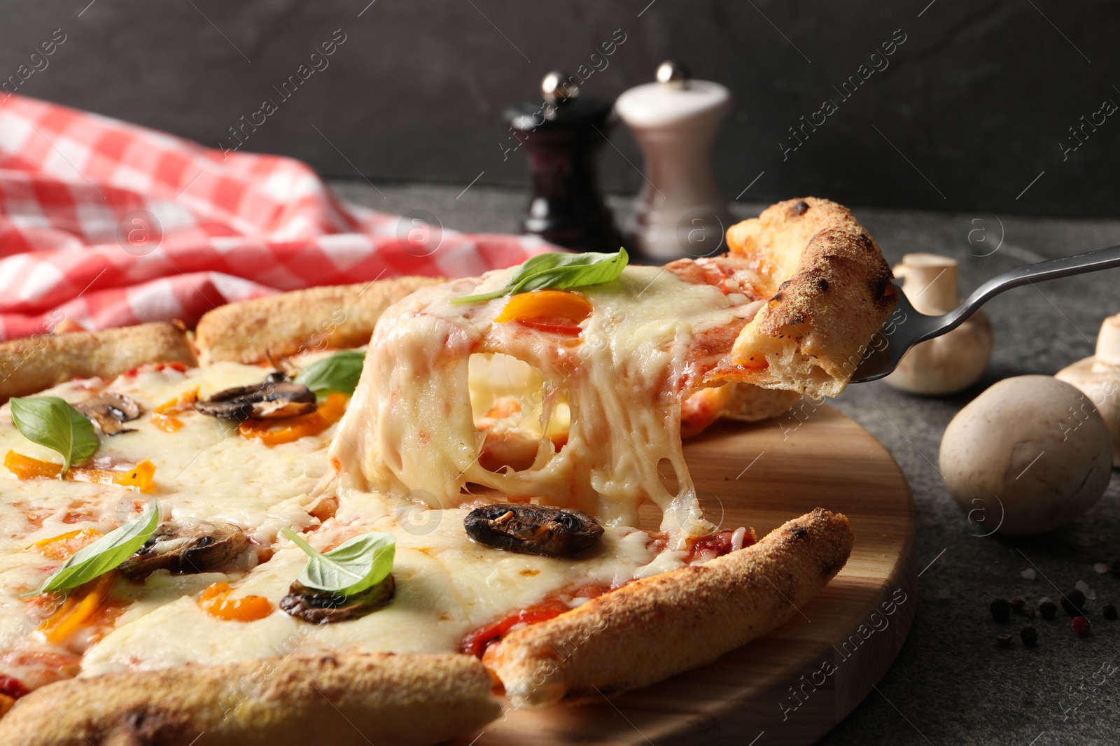 Photo of Taking piece of delicious vegetarian pizza at grey table, closeup