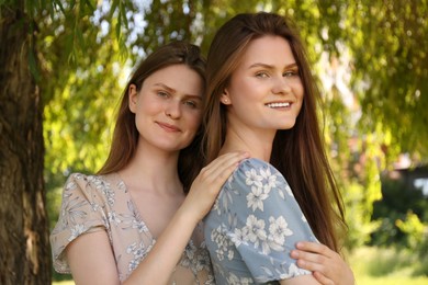 Photo of Portrait of two beautiful twin sisters in park