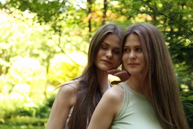 Portrait of two beautiful twin sisters in park, space for text