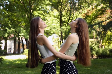 Two beautiful twin sisters spending time together in park