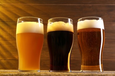 Photo of Glasses with different types of beer on wooden table, low angle view