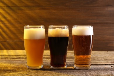 Glasses with different types of beer on wooden table